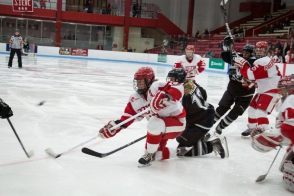 Boston, March 1, 2014 -- Boston University women's hockey defense Kaleigh Fratkin, center, and Providence College women's hockey forward Janine Weber, center right, play during the East Quarterfinals. The two may be teammates next season in NY. Photograph by Carolyn Bick. © Carolyn Bick/BUNS 2014.