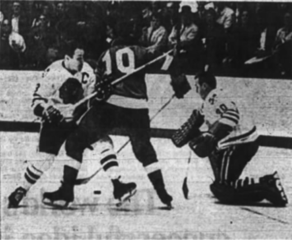Detroit's Alex Delvecchio is tied up by Hawks' Pierre Pilote in last night's game.