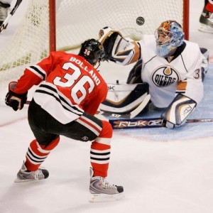 Dave Bolland knocks in a puck over Edmonton goalie Dwayne Roloson.