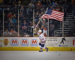 SPC Johnny Laursen carries the American flag on the ice in Cincinnati during intermission.