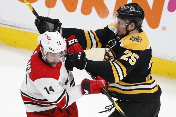 Boston Bruins defenseman Brandon Carlo (25) hits Carolina Hurricanes right wing Justin Williams