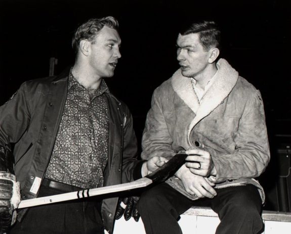 Bobby Hull #9 holds a hockey stick as he talks to teammate Stan Mikita