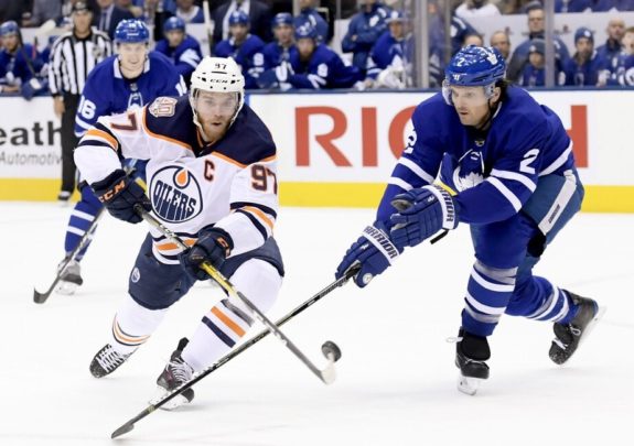 Edmonton Oilers Connor McDavid dekes around former Toronto Maple Leaf Ron Hainsey with Mitch Marner looking on